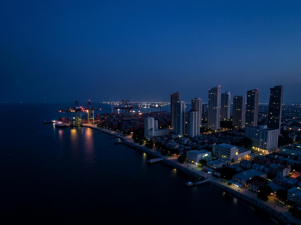 Modern African city skyline at blue-hour dusk with container port and emerging high-rises